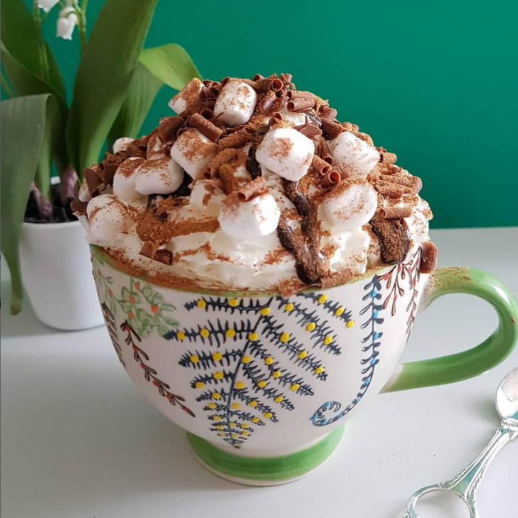 Artistic mug with hot chocolate, cream and marshmallows
